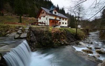 a house on the side of a river with a waterfall at Apartmaji nad potokom in Železniki