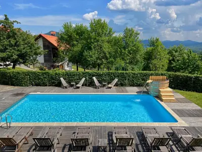 a swimming pool with lounge chairs and a swimming pool at Apartments & Rooms Domacija Krnc in Hrib pri Hinjah
