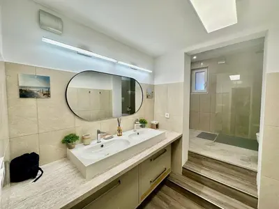 a bathroom with a sink and a mirror and a shower at New LunarGlow 3-room Apartment with free parking in Ljubljana