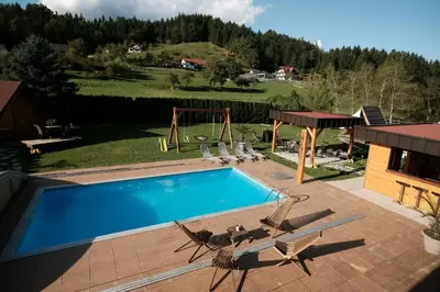 a swimming pool with two chairs and a playground at Kamp Nirvana in Šmartno ob Dreti