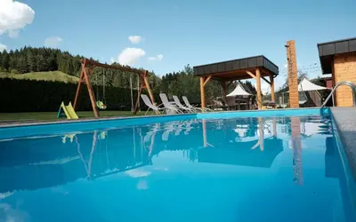 a swimming pool with chairs and a swing at Kamp Nirvana in Šmartno ob Dreti