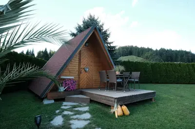 a small wooden cabin with a table and chairs at Kamp Nirvana in Šmartno ob Dreti