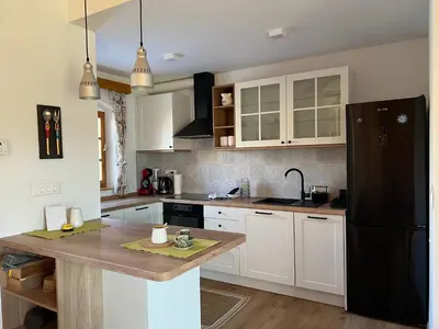a kitchen with white cabinets and a black refrigerator at Iža na brejgi in Moravske Toplice