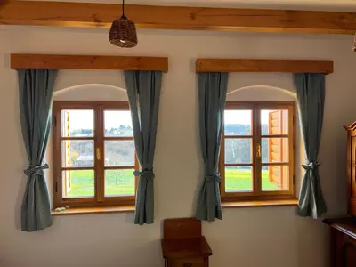 two windows with blue and white curtains in a room at Iža na brejgi in Moravske Toplice