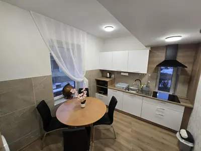 a kitchen with a table and chairs and a kitchen with white cabinets at Prenočišca Dany 4 in Dravograd