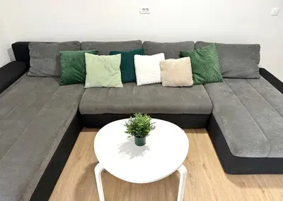 a gray couch with green pillows and a white table at Pija's apartment, a quiet getaway close to Ljubljana in Vrhnika