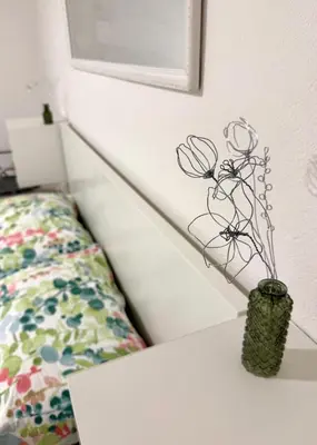 a vase with flowers on a table next to a bed at Pija's apartment, a quiet getaway close to Ljubljana in Vrhnika