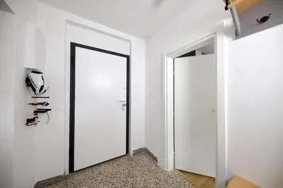 a white hallway with a door and a mirror at Baguettes apartment in Oplotnica