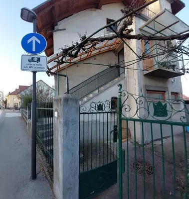a gate in front of a building with a blue sign at Being eco in Ljubljana in Ljubljana