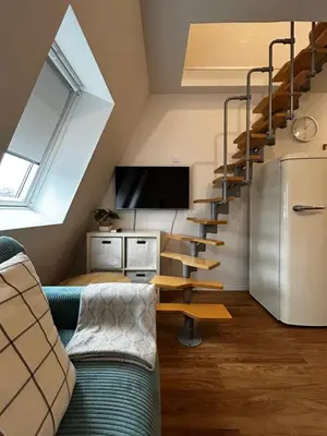 a living room with a couch and a spiral staircase at Eluma Apartments Bovec in Bovec