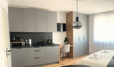 a kitchen with white cabinets and a table and a chair at Ahat apartment in Maribor