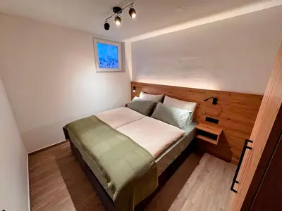 a bedroom with a large bed with a wooden headboard at Apartma Oblak in Kranjska Gora