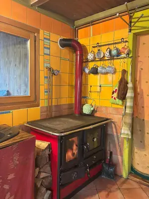 a stove in a kitchen with yellow tiled walls at Wild Art Wooden house in Ig