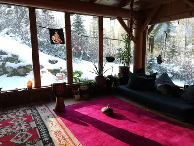 a living room with a couch in front of a window at Wild Art Wooden house in Ig