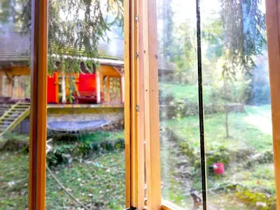 a window with a view of a house at Wild Art Wooden house in Ig