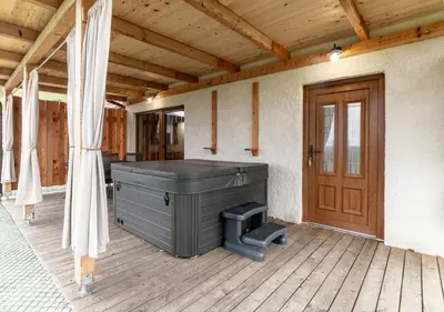a hot tub on a porch with a wooden door at Glamping Podgoro - Rogatec in Rogatec