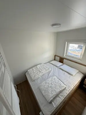 a small white room with a bed and a window at Hiška Moravska ravnica in Moravske Toplice