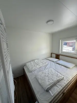 a bedroom with a bed with white sheets and a window at Hiška Moravska ravnica in Moravske Toplice