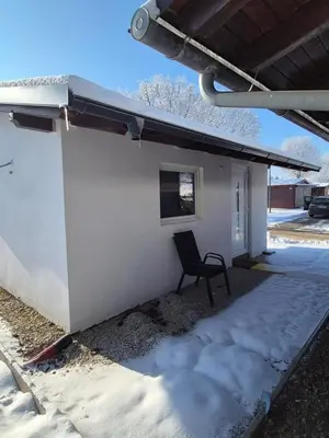 a chair sitting in front of a building in the snow at Hiška Moravska ravnica in Moravske Toplice