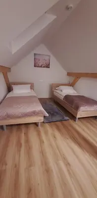 two beds in a attic bedroom with wooden floors at Gostišče Jezersko in Zgornje Jezersko