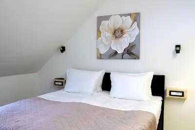 a bedroom with a bed with a flower painting on the wall at Gostišče Jezersko in Zgornje Jezersko