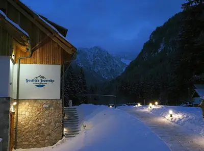 a building with a sign on it in the snow at Gostišče Jezersko in Zgornje Jezersko