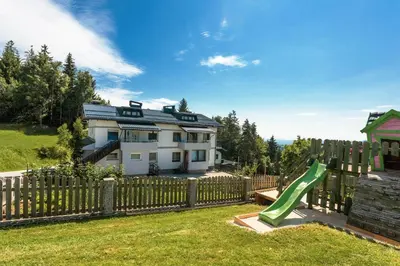 a house with a wooden fence and a green slide at Apartment Milan in Zreče