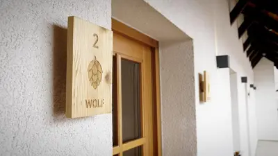 a door with a wooden sign on a wall at Turistična kmetija in pivovarna Flajs in Žalec