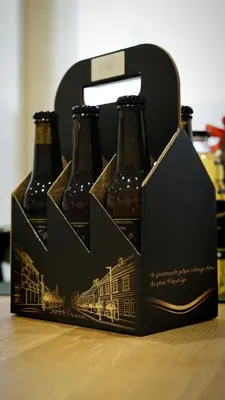 three bottles of beer in a box on a table at Turistična kmetija in pivovarna Flajs in Žalec