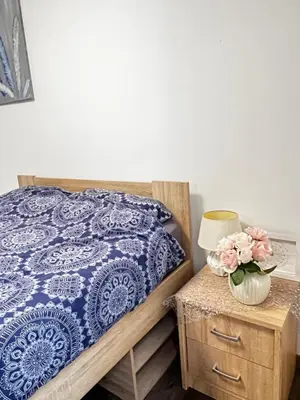 a bedroom with a bed and a table with a vase of flowers at D&D Sunny Ljubljana apartment in Vič