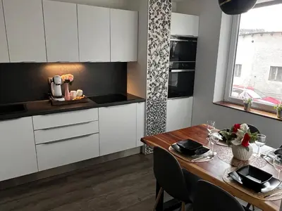 a kitchen with white cabinets and a wooden table at D&D Sunny Ljubljana apartment in Vič