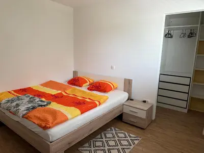 a bedroom with a bed with an orange and yellow blanket at Two bedrom Modern Flat near Ljubljana Private Garage &Balcony in Dobrova