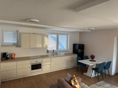 a kitchen with white cabinets and a table with chairs at Two bedrom Modern Flat near Ljubljana Private Garage &Balcony in Dobrova
