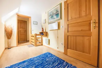 a hallway with a wooden door and a blue rug at APARTMENTS ROGLA LUKANJA 1 in Oplotnica