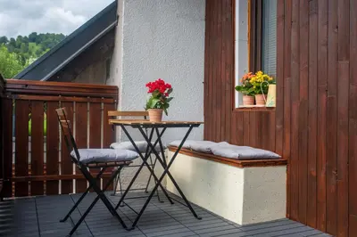 a table and two chairs on a balcony with flowers at Little Oasis Apartment in Zgornje Gorje
