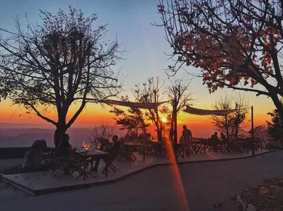 a group of people sitting at tables in front of a sunset at Penzion Sinji vrh in Zoll