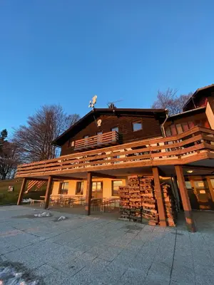a large building with a pile of logs at Planinski dom Kal in Dol pri Hrastniku