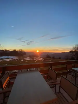 a table and chairs on a deck with the sunset at Planinski dom Kal in Dol pri Hrastniku