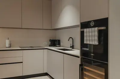 a kitchen with white cabinets and a black refrigerator at City Residence in Ljubljana