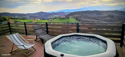 a hot tub and two chairs on a deck with a view at Vineyard cottage Mehak in Telče