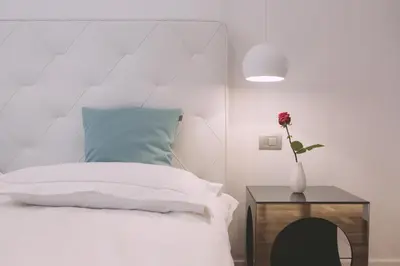 a bedroom with a white bed and a vase with a flower at Ambassador Suite Studio in Ljubljana