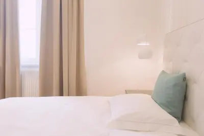 a white bed with a green pillow on it at Ambassador Suite Studio in Ljubljana