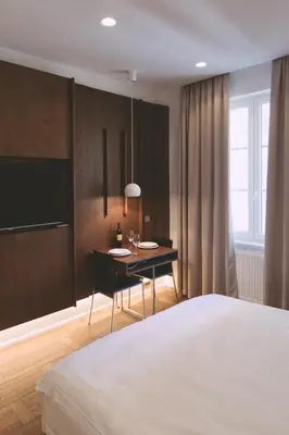 a bedroom with a bed and a desk and a table at Ambassador Suite Studio in Ljubljana