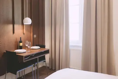a room with a table with wine glasses and a window at Ambassador Suite Studio in Ljubljana