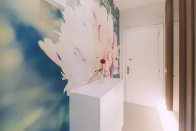 a vase with flowers on a white stand in a room at Ambassador Suite Studio in Ljubljana
