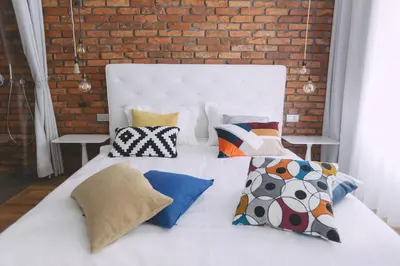 a white bed with pillows and a brick wall at Dragon's Den in Ljubljana