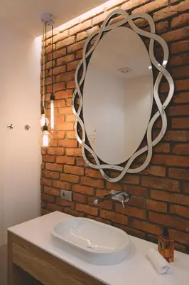 a bathroom with a sink and a mirror on a brick wall at Dragon's Den in Ljubljana