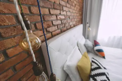 a lamp hanging on a brick wall next to a couch at Dragon's Den in Ljubljana