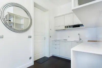 a kitchen with white cabinets and a mirror at Tivoli Double in Ljubljana