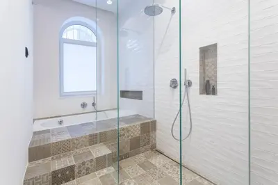 a bathroom with a glass shower with a tub at Tivoli Double in Ljubljana
